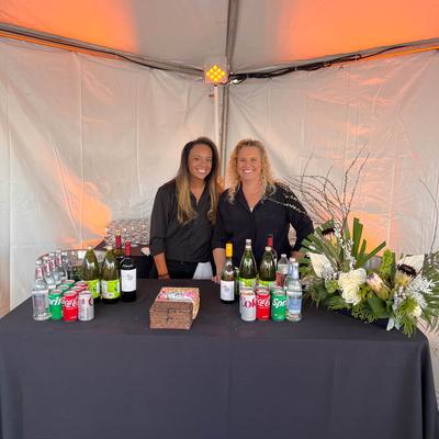 Two bartenders behind drink display table.