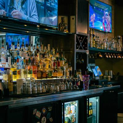 Bar area with glassware, TVs, and shelves of liquor bottles.