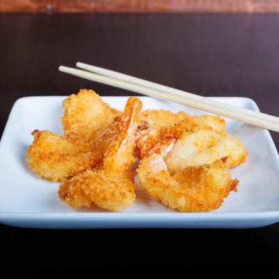Crispy fried shrimp served on a white square plate with chopsticks.