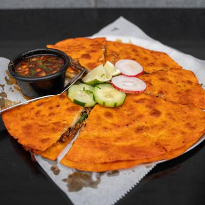 Pizza birria served with consomme, radish and cucumber slices.