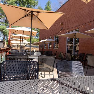 Outdoor patio tables shaded by large tan umbrellas.