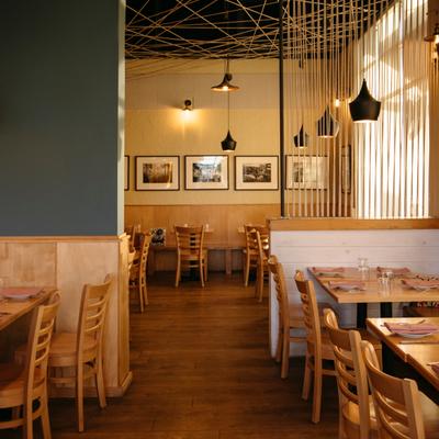 Dining area with wooden tables, wall art, and pendant lights.