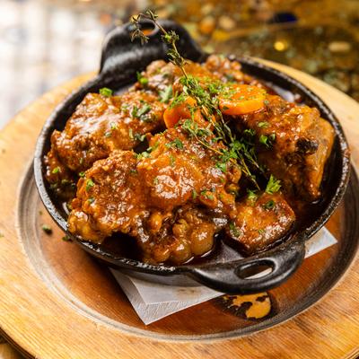Stewed meat with sauce and herbs in a cast iron skillet.