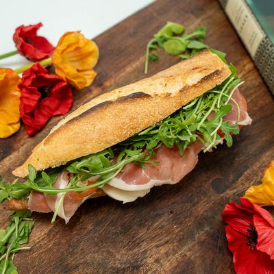 Caprese sandwich served on a wooden board with flower garnish.