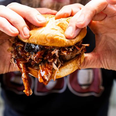 Hands holding the brisket sandwich.