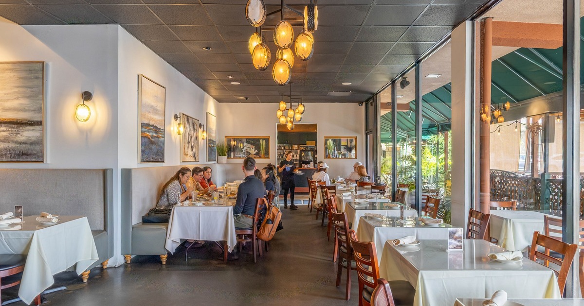 Interior, bright and elegant dining space, with large windows, chandeliers and art on the walls