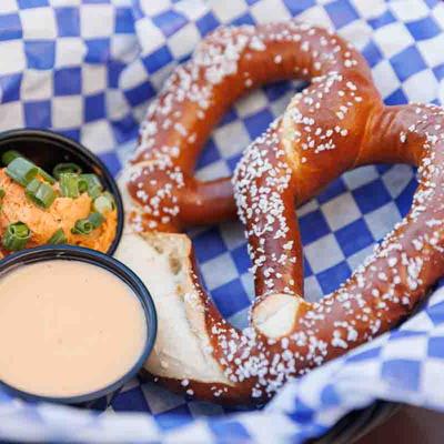 A pretzel served with cheese dip and a small salad.