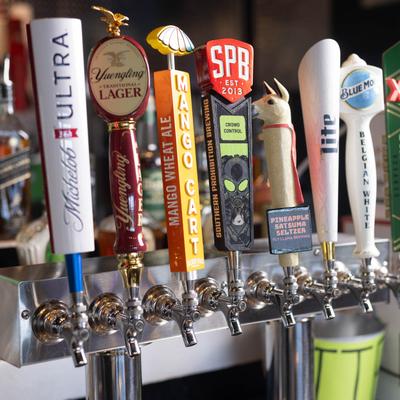 Colorful beer tap handles lined up at a bar.