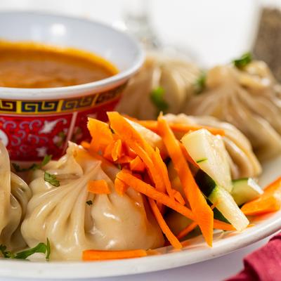 Steamed dumplings with vegetables and a chutney bowl, close up.