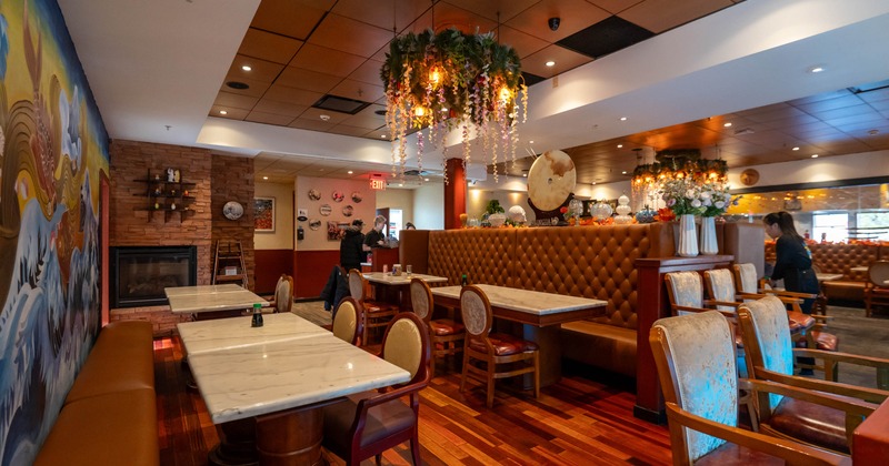 Interior, marble tables, leather booths, a colorful mural, and floral chandeliers