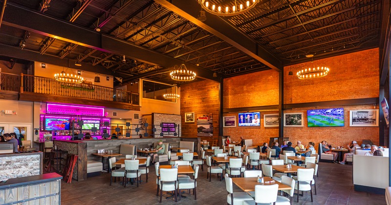 Interior, dining area, tables, chairs, bar behind, tv screens on the walls, gallery