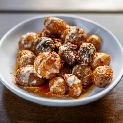 A bowl of fried marble potatoes, drizzled with sauce.