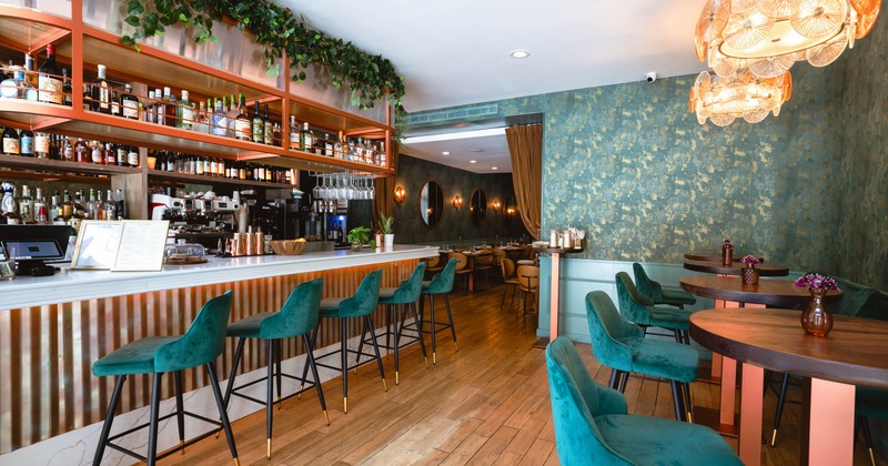 Interior, contemporary design, marble bar, teal velvet chairs, and warm lighting
