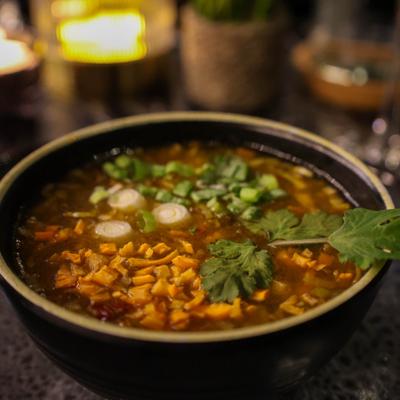 Manchurian Fire Soup garnished with green onions and fresh herbs.
