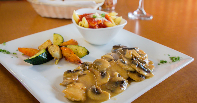 Mushrooms in a sauce, grilled seasonal vegetables and pasta, served on a plate