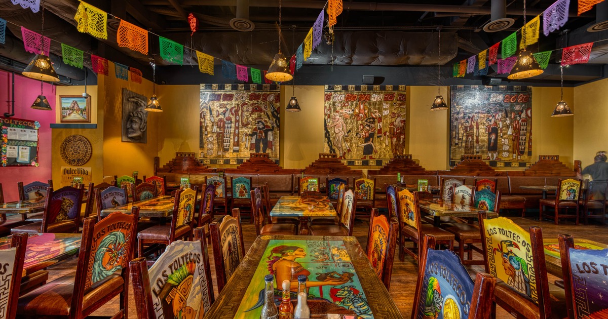 Interior of a Mexican restaurant with vibrant murals, and wooden furniture