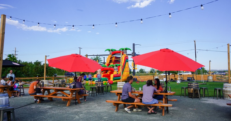 Outside, tables and seating with guests, a bouncy castle for children