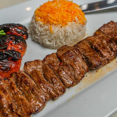 Lamb kebab served with rice and charred tomatoes.