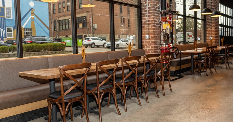 Interior, dining area, long banquette bench with tables and chairs, ready for guests