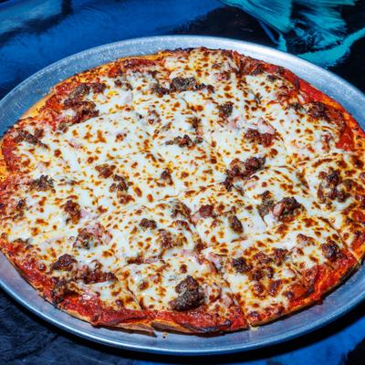 Meat lovers pizza served on a round metal tray.