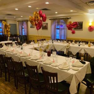 Indoor dining area set up for a large gathering, with a U shaped table set with place settings