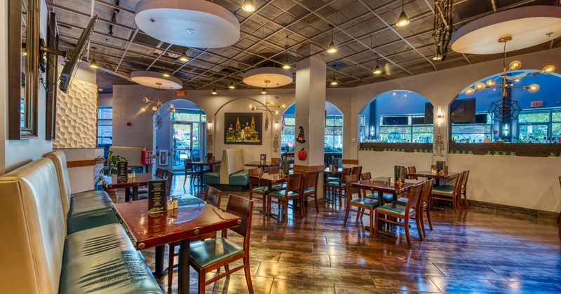 A spacious restaurant with wooden tables and chairs, booth seating, pendant lighting
