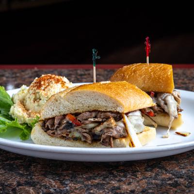 Philly Steak Sandwich served with a potato salad and lettuce.