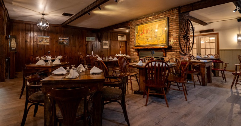 Interior, cozy dining area with wooden tables and chairs, wood covered walls, fireplace