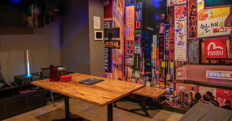 Karaoke room with a vibrant cityscape mural and wooden table