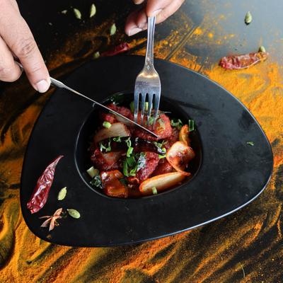 Hands holding a knife and fork and cutting meat.