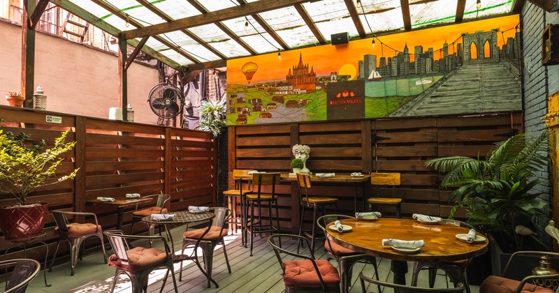 Seating area with tables, chairs and a vibrant mural of landscapes and a city skyline