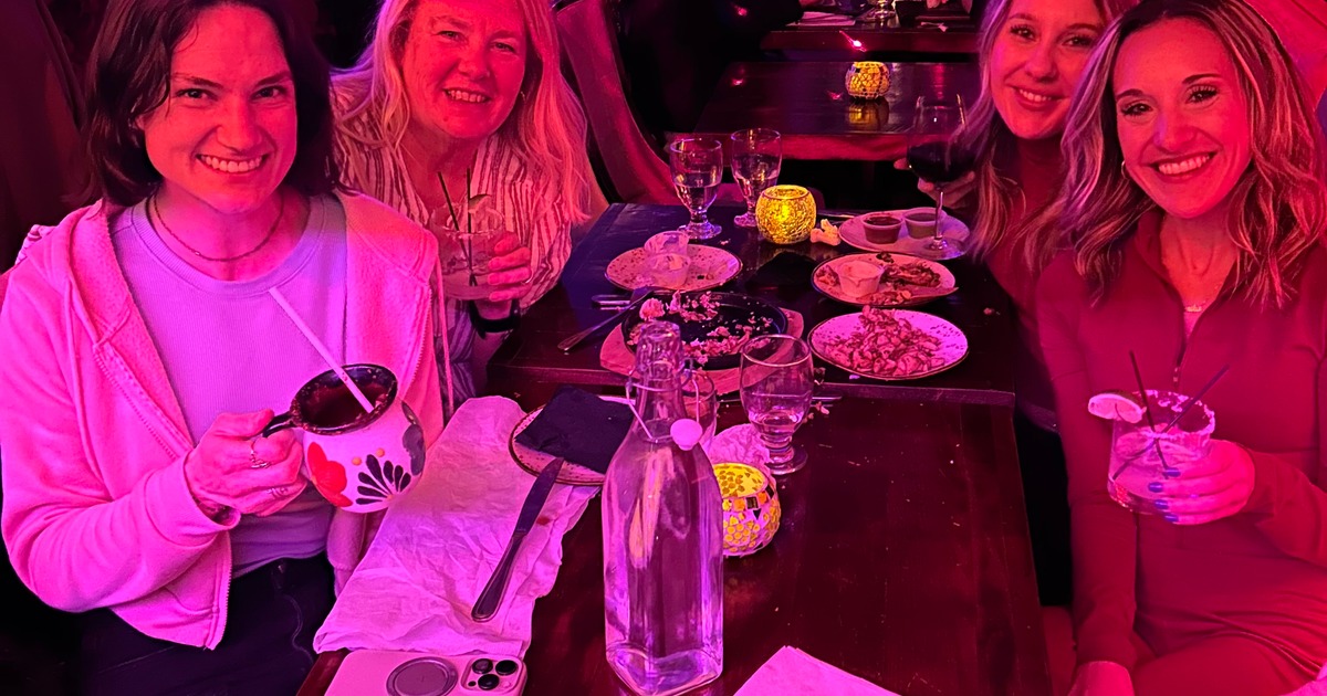 People enjoying drinks and dinner under pink lighting