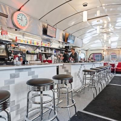 Retro diner counter with stools and overhead lighting.