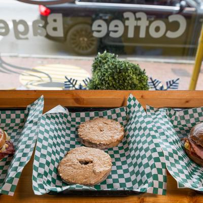 Various bagels served on trays and displyed on the counter with a street view.