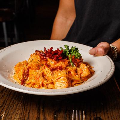 Hands holding a plate of garlic pasta with lemon basil ricotta.