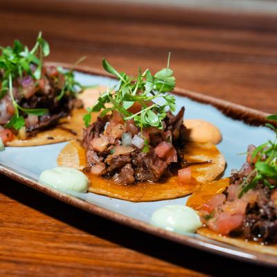 Mini tacos, with short rib, chipotle aioli, cream, onions, and cilantro.