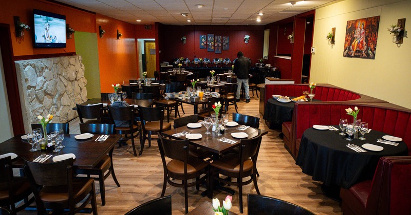 Interior, tables and chairs in dining area with paintings on the wall