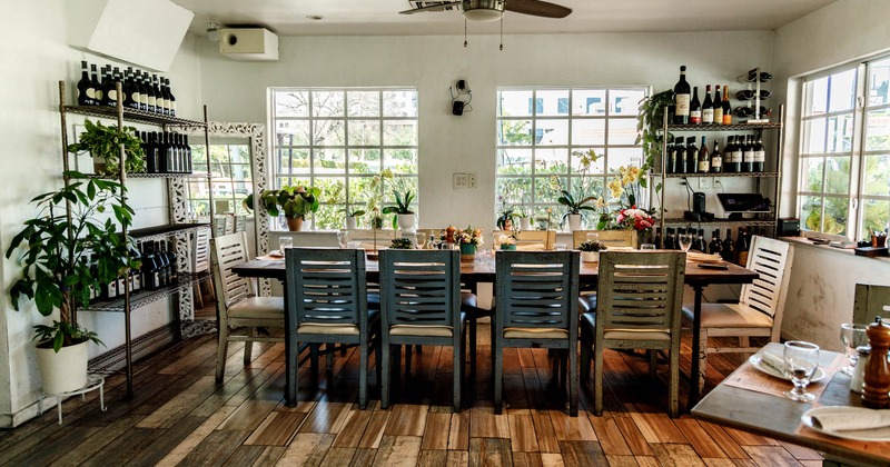 A large table in the room with wine bottles on the shelves