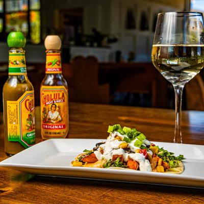 Veggie Wino Taco, with a glass of white wine and hot sauces.