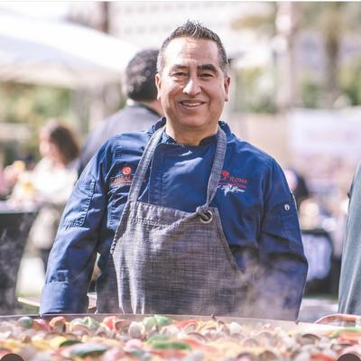 Chef smiling and making paella.