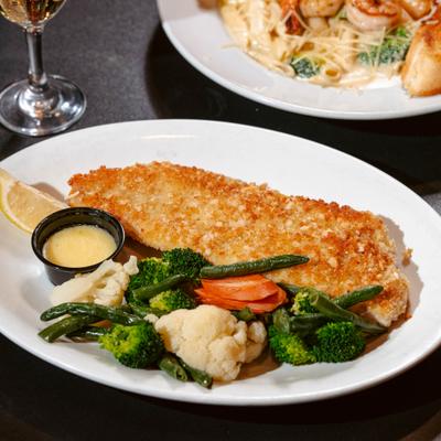 Breaded fish fillet served with mixed vegetables, dipping sauce and lemon wedge.