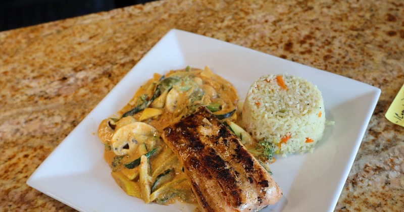 Grilled fish filet served with sauteed mushrooms and vegetables in sauce, and rice