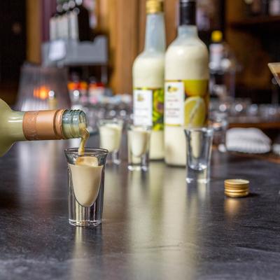 Homemade Orangecello drink shots and Espresso Martini on a bar counter.