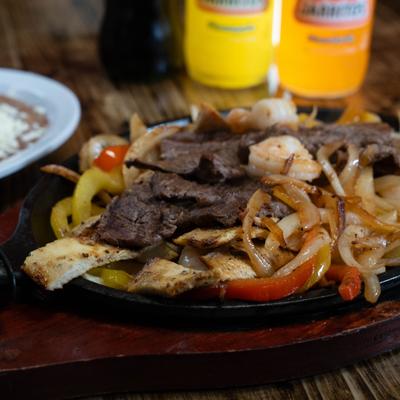 Chicken, shrimp, and steak Fajitas, with grilled onions and bell peppers.