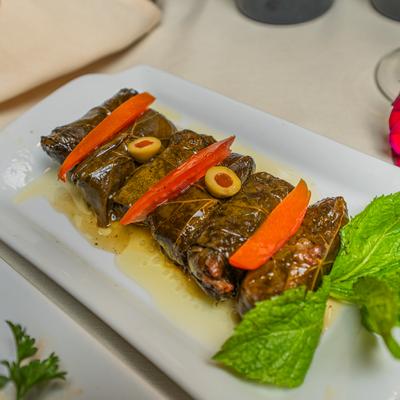Stuffed grape leaves garnished with olives and mint.