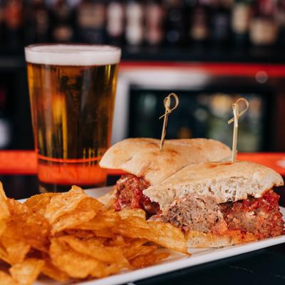 Meatball sandwich with chips and a glass of beer.