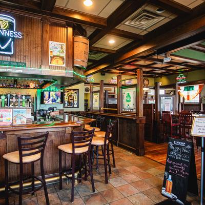 Wooden pub interior with bar seating and neon beer signs.