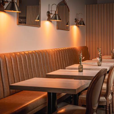 Warm booth seating with small tables and wall lamps.