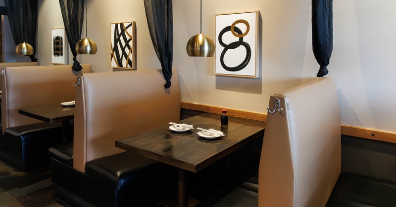 Restaurant booths - beige cushions, dark wood tables, pendant lights and abstract wall art