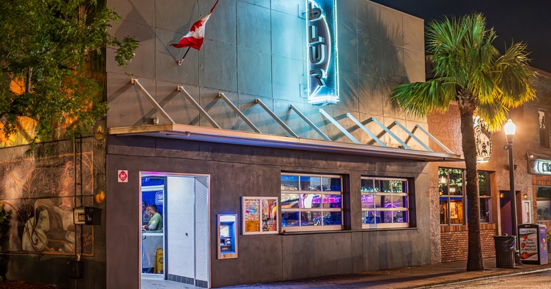 Exterior, front view to club, night, entrance, light sign